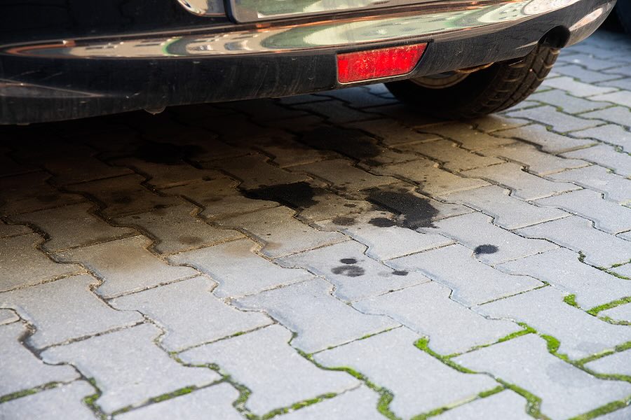Oil leaking on pavement from an old car.